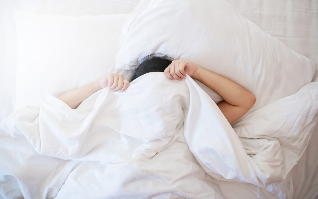 Magnesium vs. Melatonin: Finding the Right Sleep Support woman sleeping in bed covering herself with bed sheets